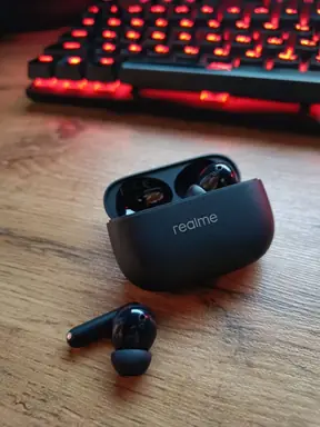 Исходное фото чёрных беспроводных наушников realme Buds T310 на столе рядом с клавиатурой